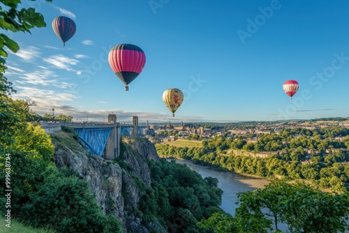 hot air balloons flying over the top. In the foreground are green trees, and below is a cliff overlooking the city of Bristol, with a clear blue sky and sunny day