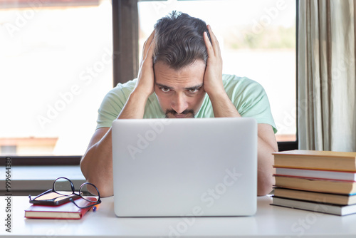 Tired and bored student sitting at the desk while preparing for exams at university 