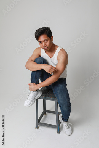 Portrait of sporty asian man posing over white background looking at the camera.