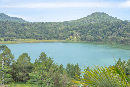 Lake and Mountain Landscape. Linau lake Tomohon. A serene view of a lake surrounded by lush green mountains. The lake reflects the blue sky and the trees in a peaceful setting. photo