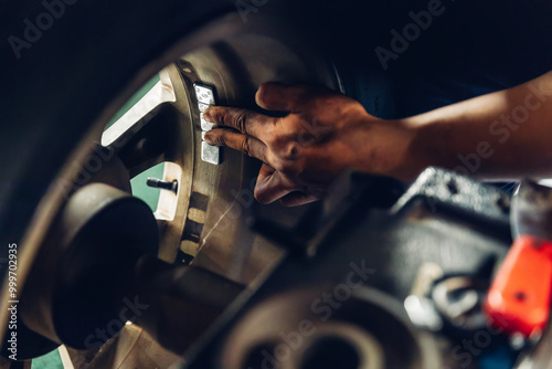 Mechanic using Wheel weights for balancing tires arrayed in trays for precise balance. Repairman Installing Wheel Balance Weight. Mechanic places weights on steel rim of machine. Balance wheel in car photo