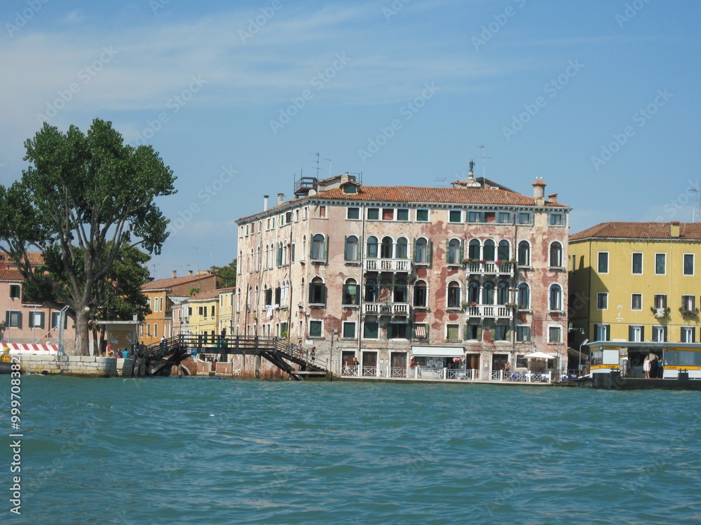 Fototapeta premium Romantic Venetian landscape. Tourists in a gondola on a walk along a Grand Canal in the old town. Famous historical heritage city.