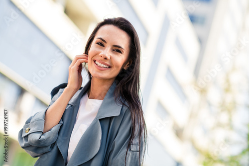 Photo of shiny attractive lady dressed grey coat smiling enjoying good weather warm wind blowing outdoors town street