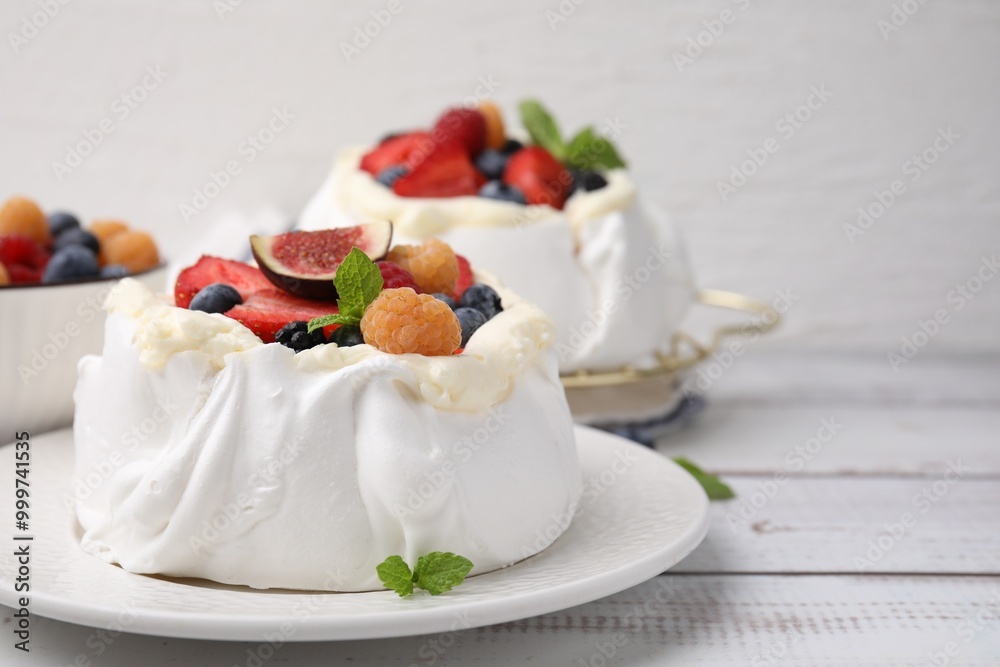 Pavlova cake (meringue dessert) with whipped cream, fresh berries, fig and mint on white wooden table, closeup Pavlova cake (meringue dessert) with whipped cream, fresh berries, fig and mint on white wooden table, closeup