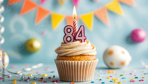 Birthday cupcake with burning lit candle with number 84. Number eighty-four for eighty-four years or eighty-fourth anniversary. photo