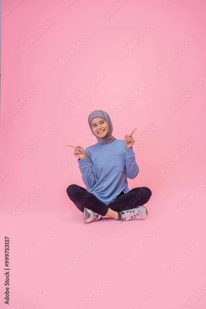 A cheerful young woman is posing confidently in vibrant sportswear against a pink backdrop A cheerful young woman is posing confidently in vibrant sportswear against a pink backdrop