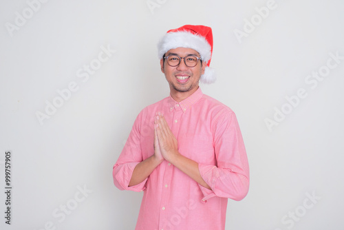 A man wearing santa hat doing greeting pose photo