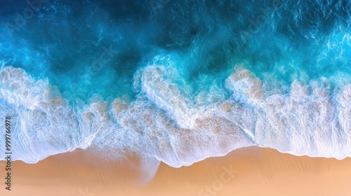 Aerial view of ocean waves meeting sandy beach, showcasing nature's beauty and tranquility.