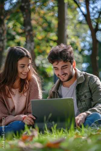 A couple sitting in the grass, engaged in outdoor activity, using a laptop