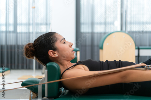 A young woman doing pilates exercises on a pilates reformer