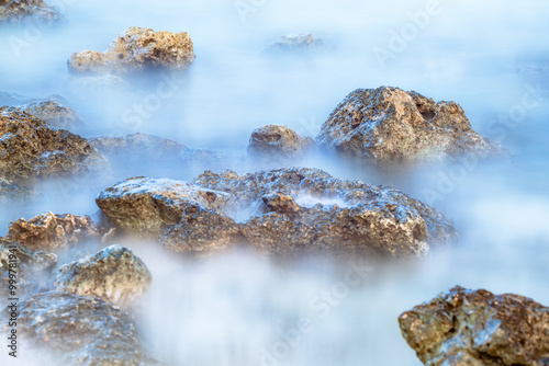 Long Exposure Capture of Rocky Shoreline. Stunning Ocean Views Enveloped in Mist. photo