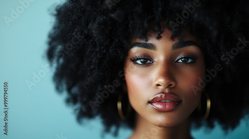 A stunning image of a woman with captivating natural hair set against a soft blue background, highlighting elegance and empowerment through contemporary portraiture.