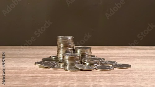 Close up of male hand stacking coins on the wooden table. Money saving, cost and budget or investment concept.