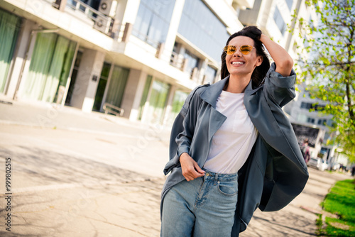 Photo of sweet lovely girl wear grey trench dark glasses smiling enjoying sunny weather outdoors urban city street
