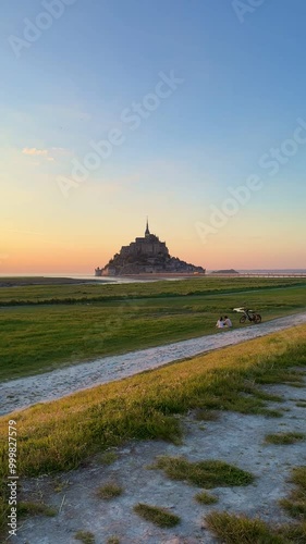 Wallpaper Mural Romantic sunset date with stunning views of Mont Saint Michel, Normandy, France. Couple with bicycle in a field watching sunset. Torontodigital.ca