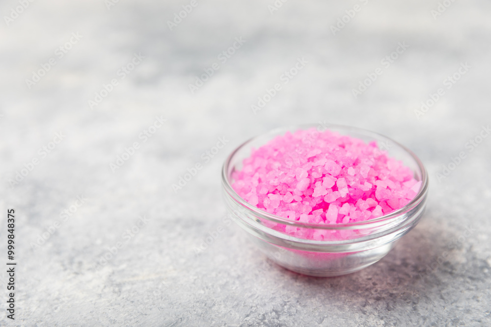 Sea salt for bath with aroma and rose flowers on textured wooden background. Pink sea salt. Spa treatments. Natural salt with herbs and essential oils. skincare concept. Meso for text. Copy space