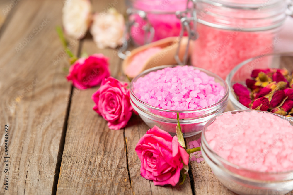 Sea salt for bath with aroma and rose flowers on textured wooden background. Pink sea salt. Spa treatments. Natural salt with herbs and essential oils. skincare concept. Meso for text. Copy space Sea salt for bath with aroma and rose flowers on textured wooden background. Pink sea salt. Spa treatments. Natural salt with herbs and essential oils. skincare concept. Meso for text. Copy space