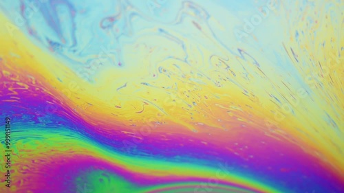 Close-up macro of colorful iridescent moving soap film surface, abstract vibrant rainbow colored pattern and texture background
