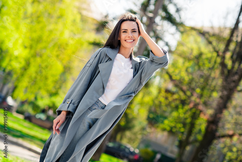 Portrait photo of beautiful young smiling latin attractive lady model posing touching her brunette hair outdoors autumn season park