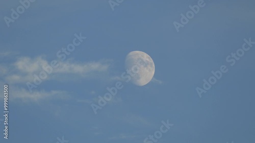 close view of the moon during the day, full moon view of the moon on a blue and cloudy day,