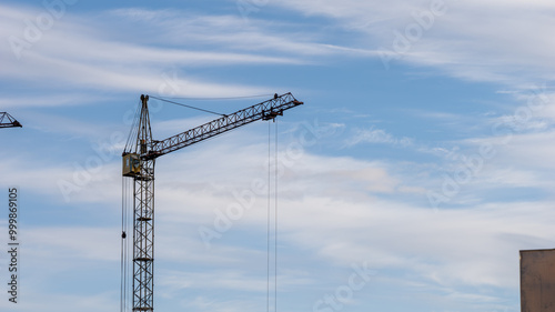 A crane is standing tall in the sky above a cloudy day