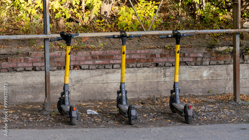 Three scooters are parked next to a brick wall photo