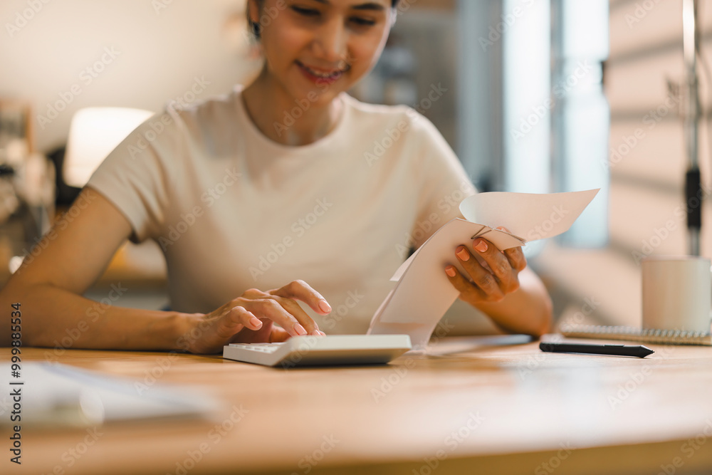 Person using calculator while holding bills reviewing financial documents related to taxes and mortgage. The scene conveys a sense of focus and diligence in managing personal finances. Person using calculator while holding bills reviewing financial documents related to taxes and mortgage. The scene conveys a sense of focus and diligence in managing personal finances.