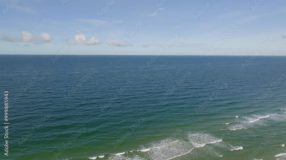 Relaxing Ocean Waves Gently Crash on the Sandy Beach Under a Clear Blue Sky During Midday at the Coast Relaxing Ocean Waves Gently Crash on the Sandy Beach Under a Clear Blue Sky During Midday at the Coast