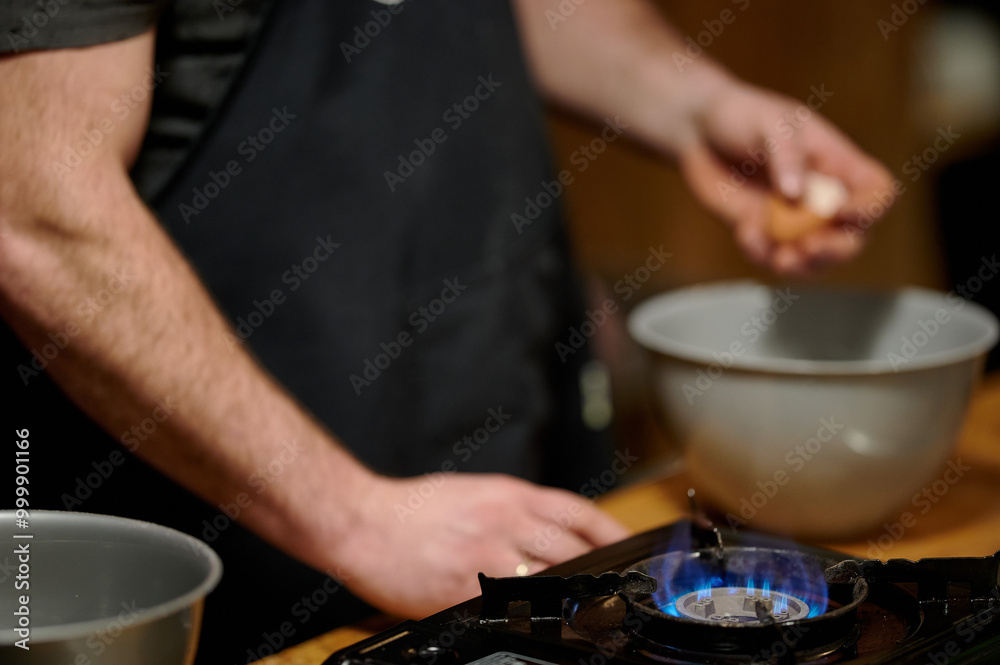 Cooking Action: Cracking an Egg Over a Bowl on a Stove Top, Amidst a Warmly Lit Kitchen Scene with Active Blue Flame