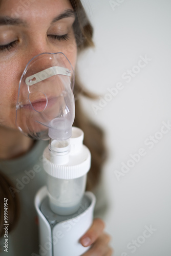 A girl breathes with the help of a nebulizer inhaler for the treatment of colds and coughs during the cold season