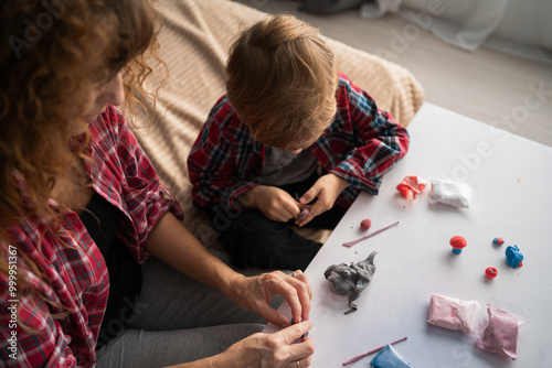 Mother and baby are making a model from plasticine or from toy colored dough, view from above