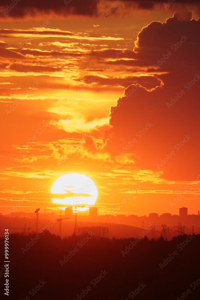 Sunset over cityscape with silhouette of cranes and buildings against an orange sky. City skyline photography for poster, wallpaper, banner, vertical. Sunset over cityscape with silhouette of cranes and buildings against an orange sky. City skyline photography for poster, wallpaper, banner, vertical.