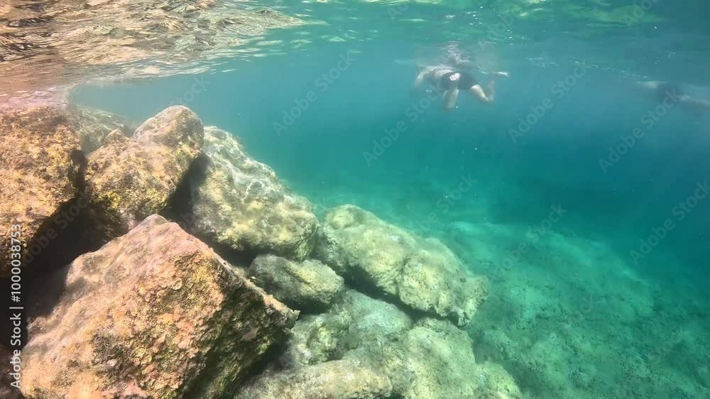People snorkeling in the shallow sea with fish and big stones. Seascape with rocks and swimming tourists. Blue green ocean, marine life in the water. Travel video from snorkeling trip. People snorkeling in the shallow sea with fish and big stones. Seascape with rocks and swimming tourists. Blue green ocean, marine life in the water. Travel video from snorkeling trip.