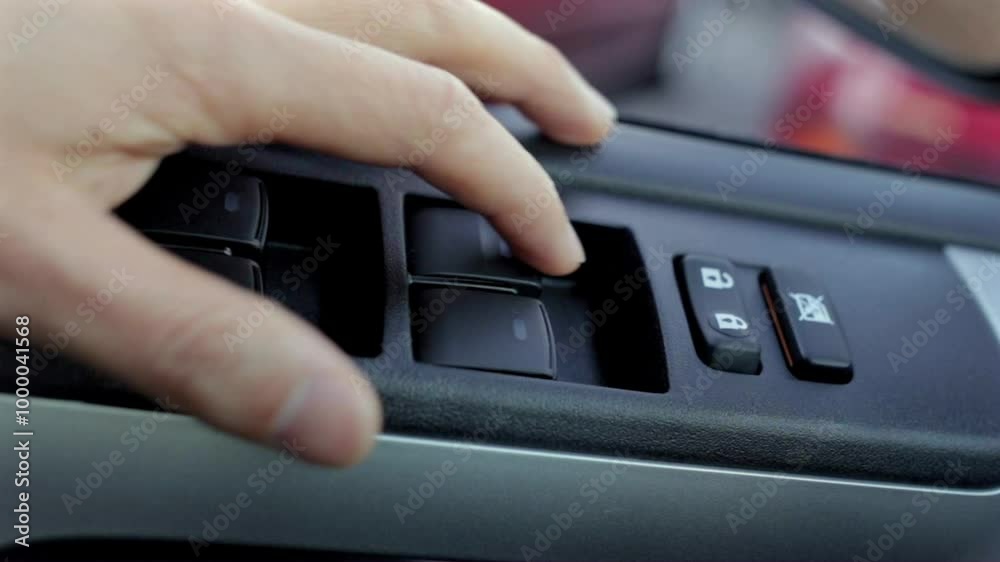 Close-up of a hand adjusting the car window control button on the driver's door panel. Showcasing the interior car controls and functionality Close-up of a hand adjusting the car window control button on the driver's door panel. Showcasing the interior car controls and functionality