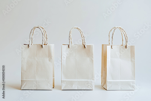 Three plain white shopping bags with twisted handles on a light background photo