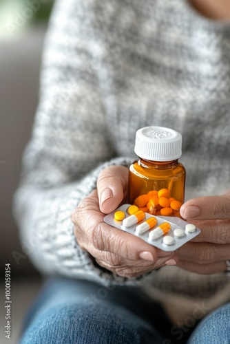 Elderly person holding a bottle of medication and a blister pack while sittin...