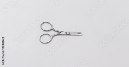 Small stainless steel scissors with curved handles on neutral background, ideal for precise cutting tasks.