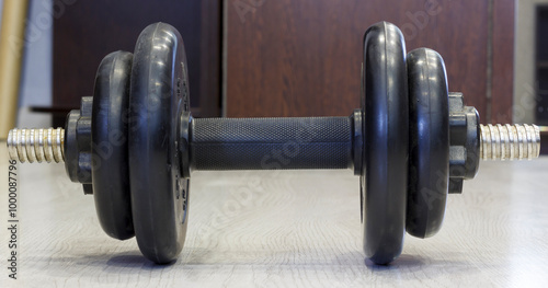 A close up of single adjustable dumbbell resting on wooden floor, ideal for fitness or home gym themes.