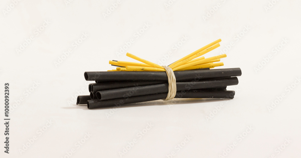 A bundle of black and yellow heat shrink tubes secured with rubber band, isolated on white background. A bundle of black and yellow heat shrink tubes secured with rubber band, isolated on white background.