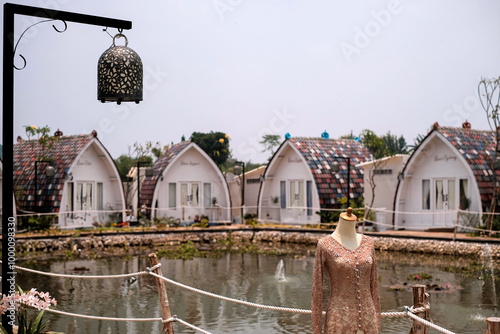 A long-sleeved bridal kebaya in light brown, adorned with elegant embellishments, perfect for a traditional Indonesian wedding from West Java’s Sundanese culture. The background features a serene lake