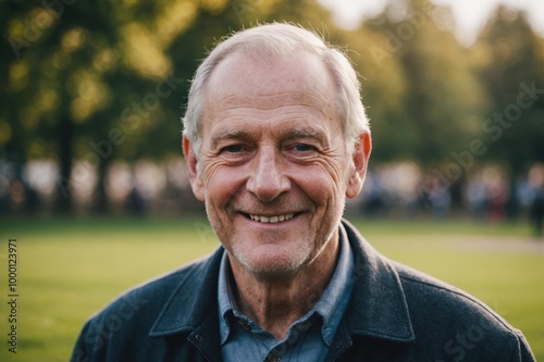 Close portrait of a smiling senior British man looking at the camera, British outdoors blurred background