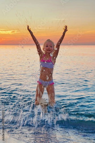 Obraz na plátně Child's joy playing in the water at sunset
