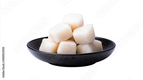 Fresh white sugar cubes in a black bowl on a white background. photo