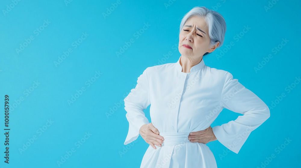 A senior woman in a flowing white outfit, wincing as she supports her aching back, symbolizing the toll of spine pain on the elderly, against a minimal background with space for te A senior woman in a flowing white outfit, wincing as she supports her aching back, symbolizing the toll of spine pain on the elderly, against a minimal background with space for te