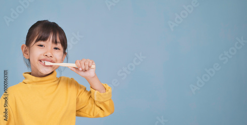 The girl is brushing her teeth and cleaning her mouth.