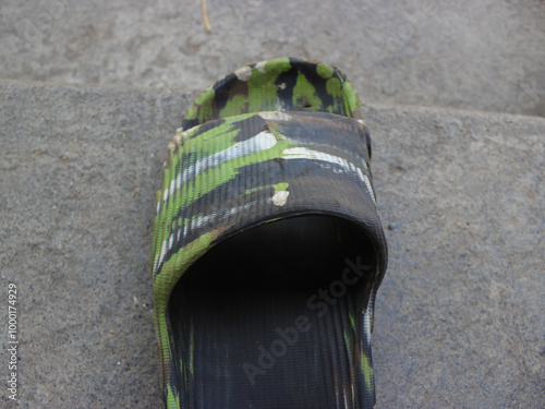 green and black abstract patterned left slip-on sandal on the floor  photo