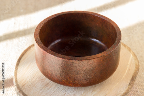 A flower pot for bonsai in red-brown color on a wooden cut.