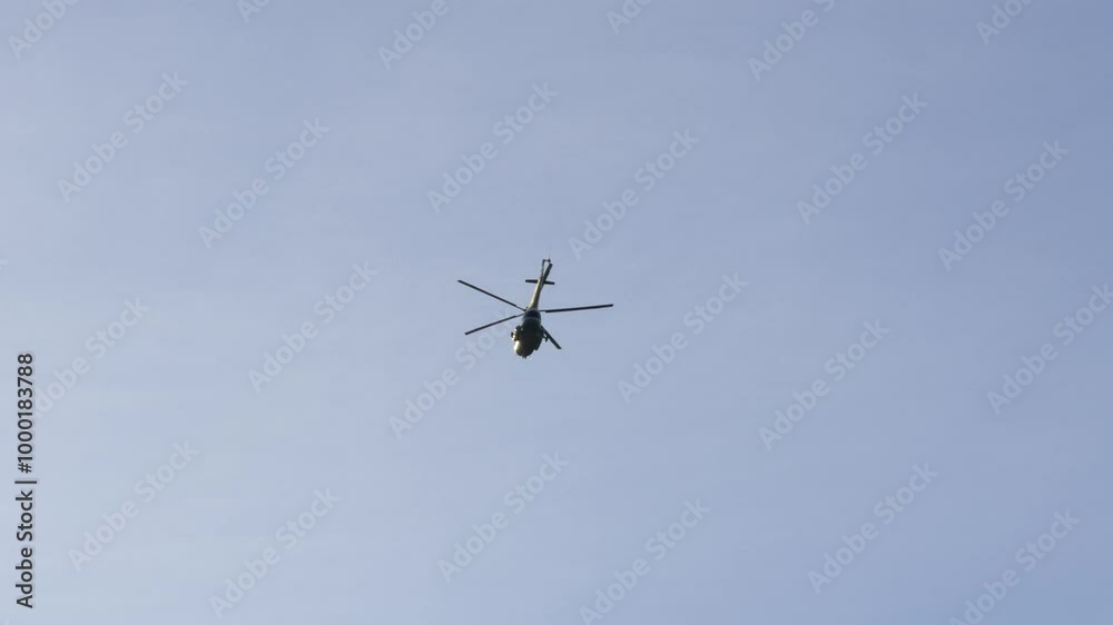 A large helicopter captured mid-flight with clear visibility against a bright blue sky. The low-angle shot shows the helicopter's structure in motion, highlighting its propellers and tail in action A large helicopter captured mid-flight with clear visibility against a bright blue sky. The low-angle shot shows the helicopter's structure in motion, highlighting its propellers and tail in action