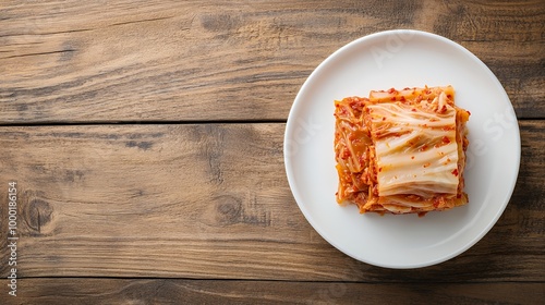 Kimchi on a white plate against a wooden background.