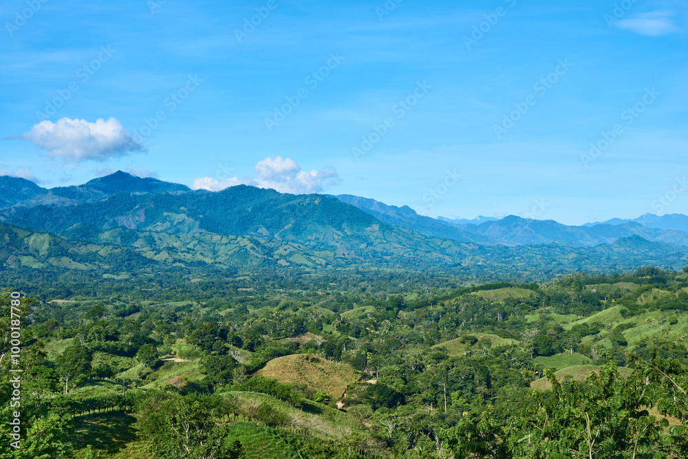 Green mountain range with blue sky and clouds, hills with trees, abundant vegetation and grass Green mountain range with blue sky and clouds, hills with trees, abundant vegetation and grass